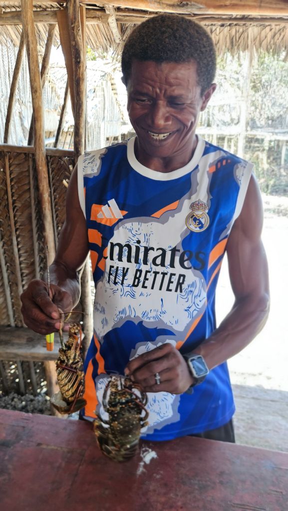 Comorian men holding a lobster, Comoros